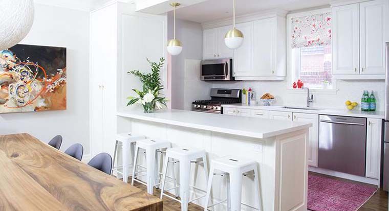 White quartz countertops in a white kitchen with a pink accent wall
